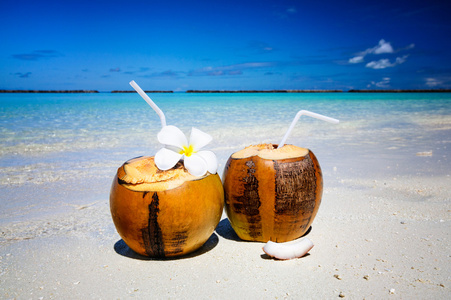 在旁边清洁海水白色沙滩上的两个椰子鸡尾酒。渡假 旅游的概念