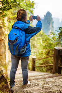 女游客与蓝色背包和智能手机拍照