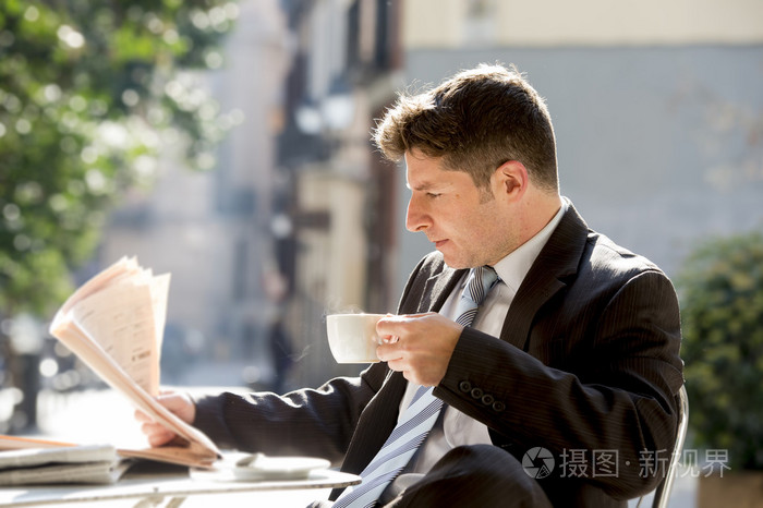 坐在户外早餐暂停早上看报纸喝咖啡新闻的商人