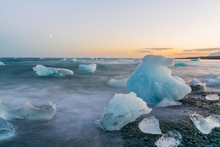 在日落时在 Jokulsarlon，冰岛的黑色沙滩上的冰山