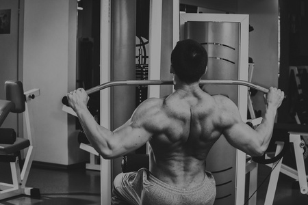 强壮的肌肉男在健身房里锻炼。在黑白照片上美丽的身体。健康的生活方式