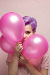 在微笑背后气球的粉红色粉彩粉彩紫短头发的女人