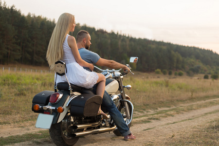 年轻情侣在一辆摩托车上的字段中