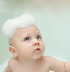在浴室里洗她的头部，洗发水泡沫的孩子