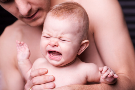 年轻的父亲喂养他的宝贝 daughter.baby 在父亲手中哭泣的女孩