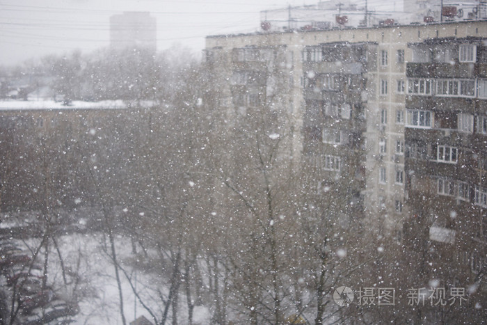 在城市的背景下, 窗外正在下雪.