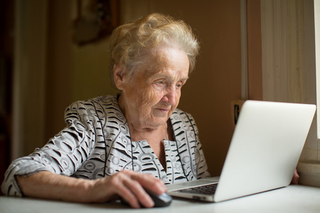 老妇在笔记本电脑上工作