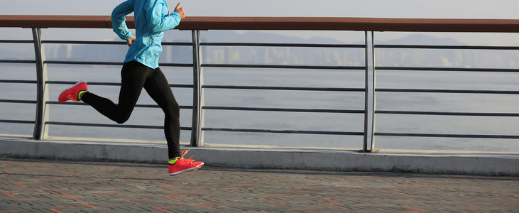 年轻的健身女人在海边跑步