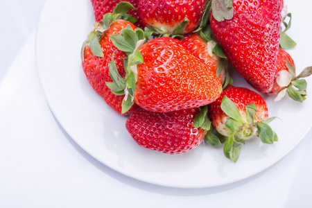草莓红白色板和一个白色的背景，对比鲜明的形象。顶尖的侧面图。夏季红色浆果。一系列的彩色照片
