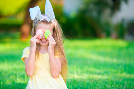 可爱的小女孩，穿着复活节兔子耳朵鸡蛋在春日
