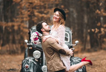 浪漫的童话婚礼情侣接吻和拥抱在松树林附近复古车