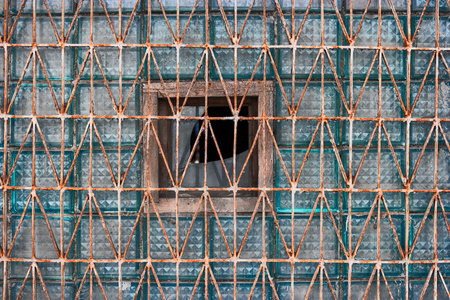 玻璃块的旧窗口覆盖着生锈网格结构设计