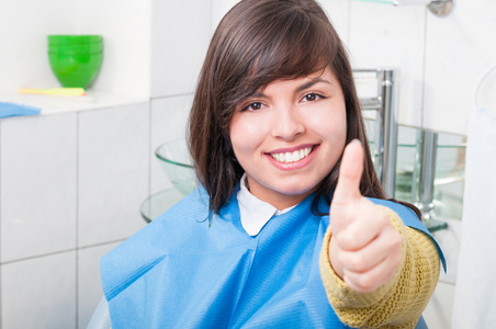 有魅力的年轻女子在牙科诊所竖起大拇指