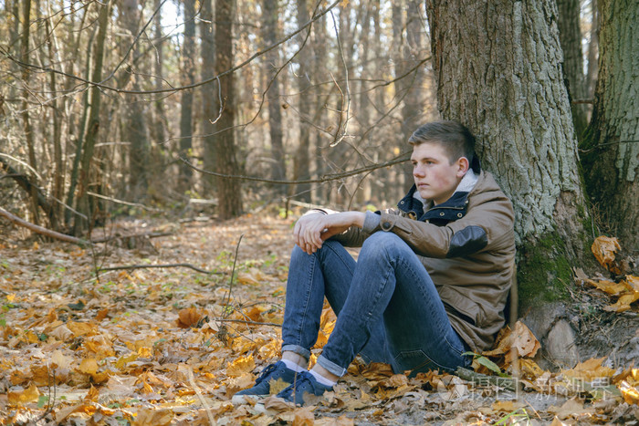 独自一人坐在树下在森林里的年轻人