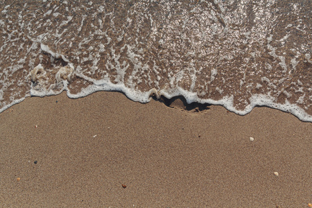 海浪冲走了沙地上的脚印。抽象背景