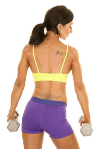女人在绿色运动胸罩和紫色短裤退缩权重