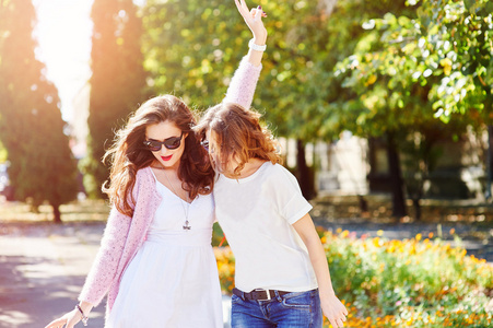 两个年轻快乐的女人行走在夏天城市