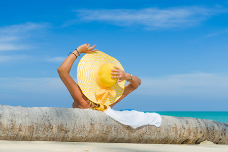 戴一顶黄色的帽子在热带海滩比基尼的女人