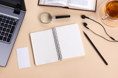 办公室的桌子桌上用品，白色空白记事本，杯，钢笔，pc，弄皱的纸，花上木制的背景。顶视图