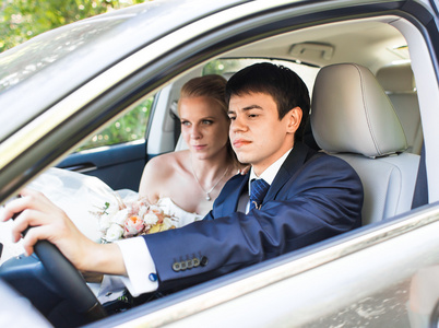 新娘和新郎在车里。他们很高兴