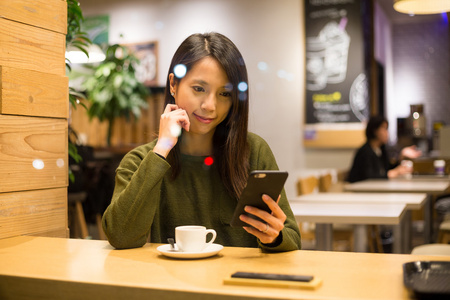 在咖啡馆里使用智能手机的女人