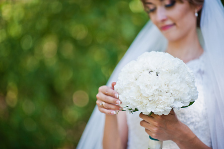 白色的康乃馨手头的新娘的婚礼花束