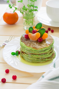 绿色煎饼与菠菜和香蕉装饰柑橘 薄荷和小红莓