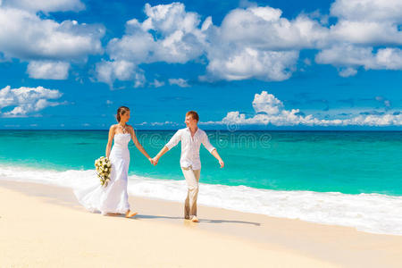快乐的新郎新娘在热带海滩上玩得开心