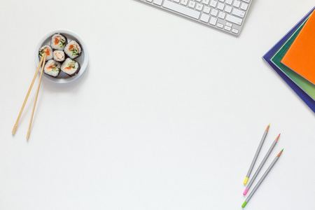 办公室工作地点与寿司的白色桌子上的顶视图