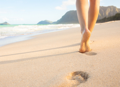 走在沙滩上的女人在沙滩上留下脚印
