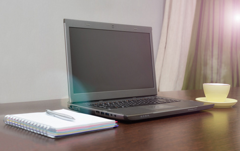 笔记本电脑通讯簿 杯子和钢笔在桌子上。太阳耀斑