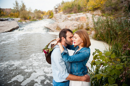 美丽的夫妇互相拥抱附近的一条山涧河流
