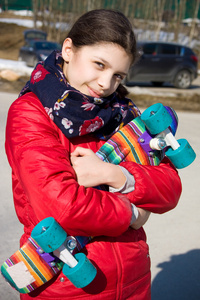 微笑女孩抱着彩色塑料佩妮板或滑板户外