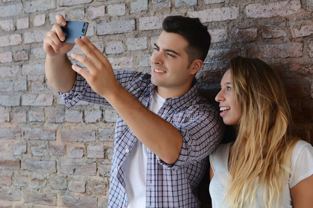 对年轻的夫妇采取自拍照与智能手机