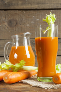 新鲜的胡萝卜汁与胡萝卜和芹菜上深色木制背景