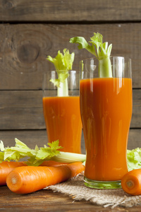 新鲜的胡萝卜汁与胡萝卜和芹菜上深色木制背景