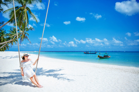 美丽的女人在一个热带的海滩，帕岸岛岛上荡秋千。泰国