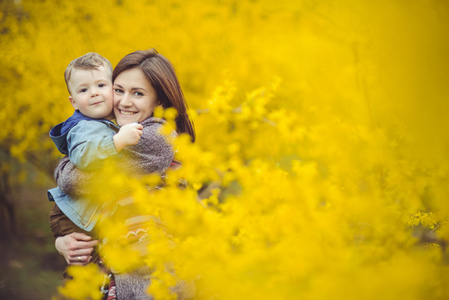 母亲和儿子快乐在公园附近黄色的花