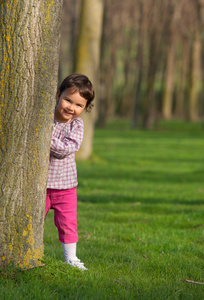 漂亮的小女孩窥视从树后