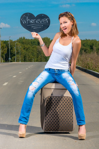 年轻漂亮的女孩与一个手提箱在路上