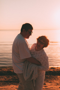 成人夫妇拥抱在日落的时候海
