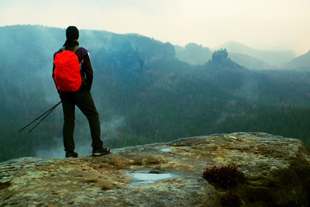 用锋利的砂岩岩的岩石帝国公园和注视着雾气很重，雾春谷红色背包徒步旅行者