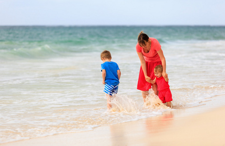 母亲和两个孩子在海滩玩