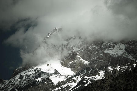 云层躺在白雪覆盖的岩石顶部。 景观。 吨