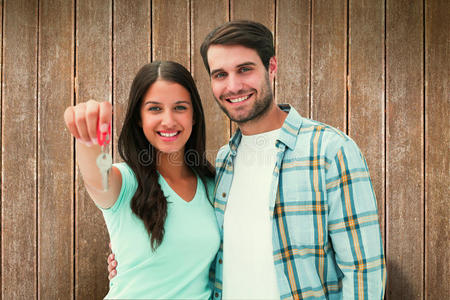 喜气洋洋的年轻夫妇展示新房子钥匙的合成图片