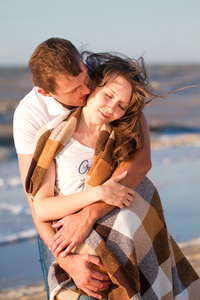 在爱情上海滩裹在毯子里的年轻夫妇
