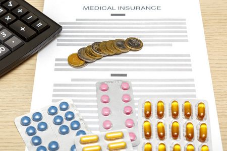 硬币 药片和计算器铺设上医疗保险费的空白