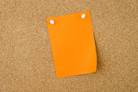 空白的橙色纸币寄托在软木板