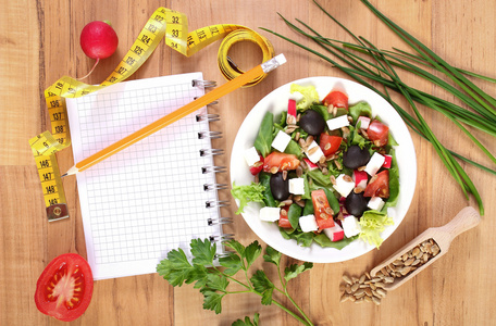 希腊色拉拌蔬菜 厘米 记事本写笔记 健康营养和减肥概念