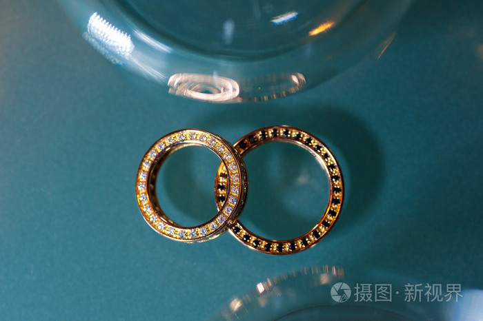 绿松石闪光背景上的两个金戒指